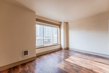 An empty living room with hard wood floors and a large window